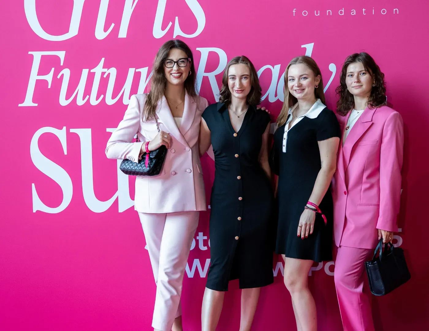 Four young women together in front of the Girls Future Ready Summit backdrop