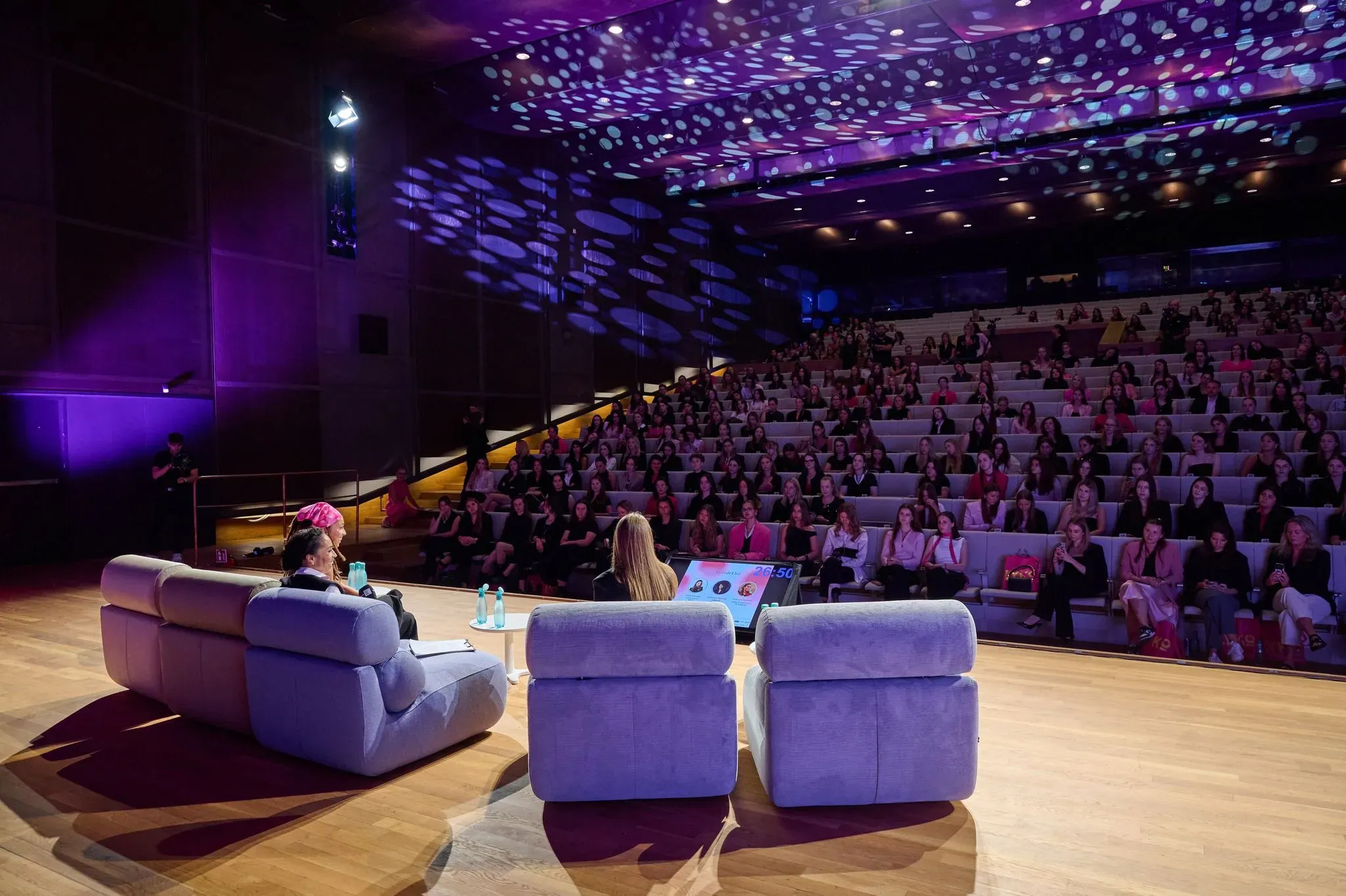 Speakers on stage at the GFR Summit in front of a full auditorium of young women