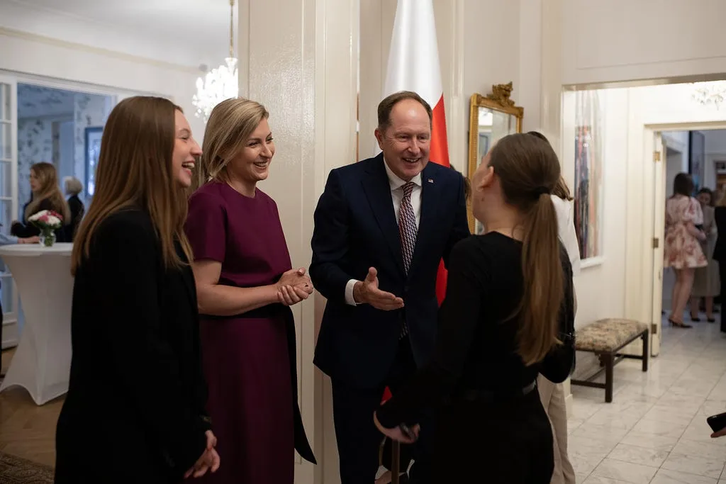 Two participants in conversation with the hosts at the gala, a Polish flag behind them