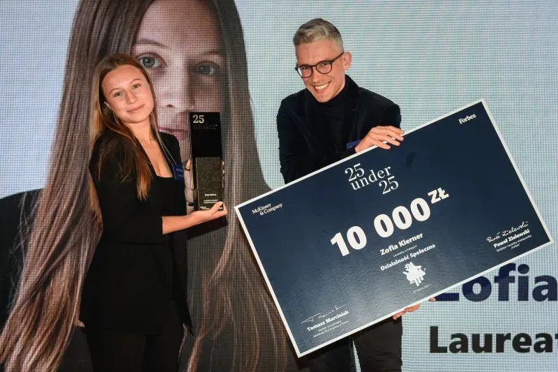 Zofia Kierner on stage holding the Forbes 25 Under 25 award and its prize cheque