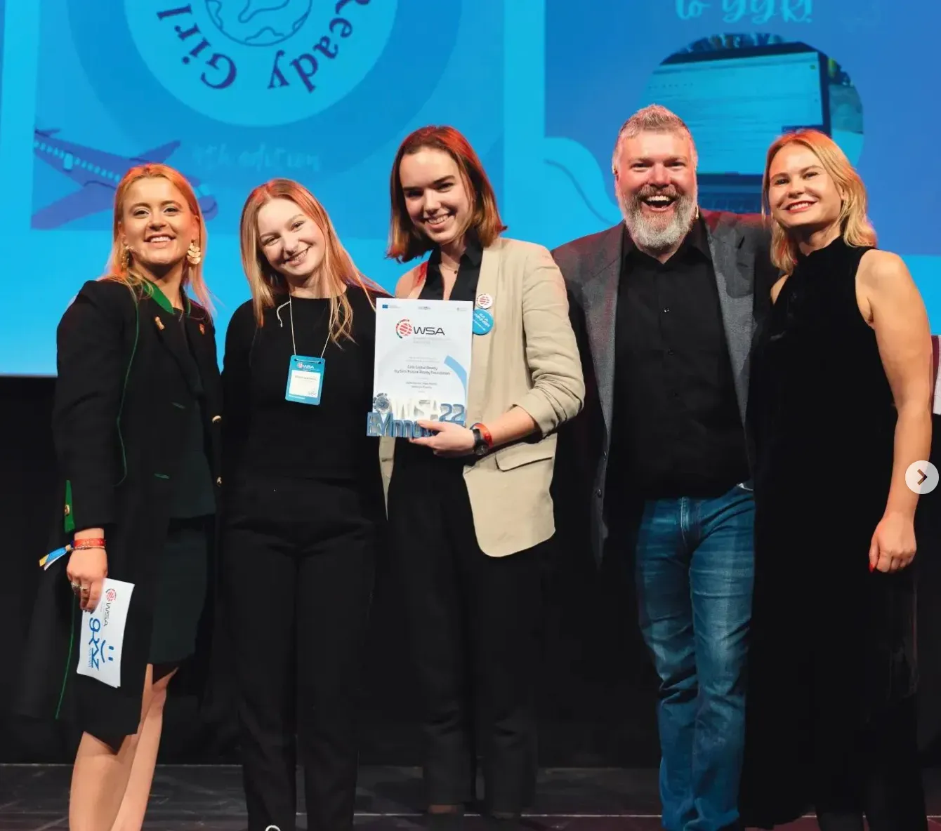 The Girls Global Ready team receiving their award on a lit stage
