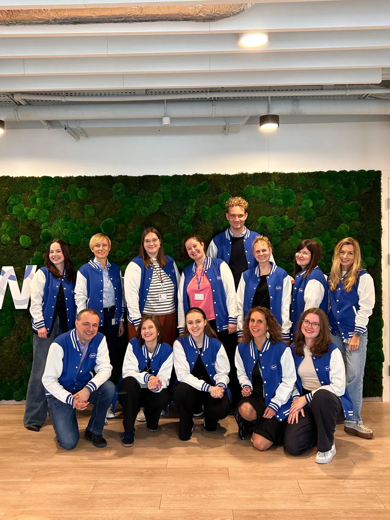 The first Youth Advisory Board together in matching jackets in front of a moss wall